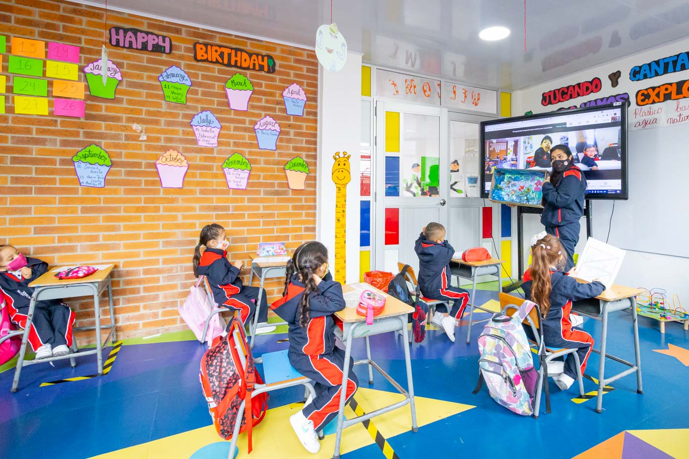 Salón de clase con estudiantes y docente usando recursos digitales
