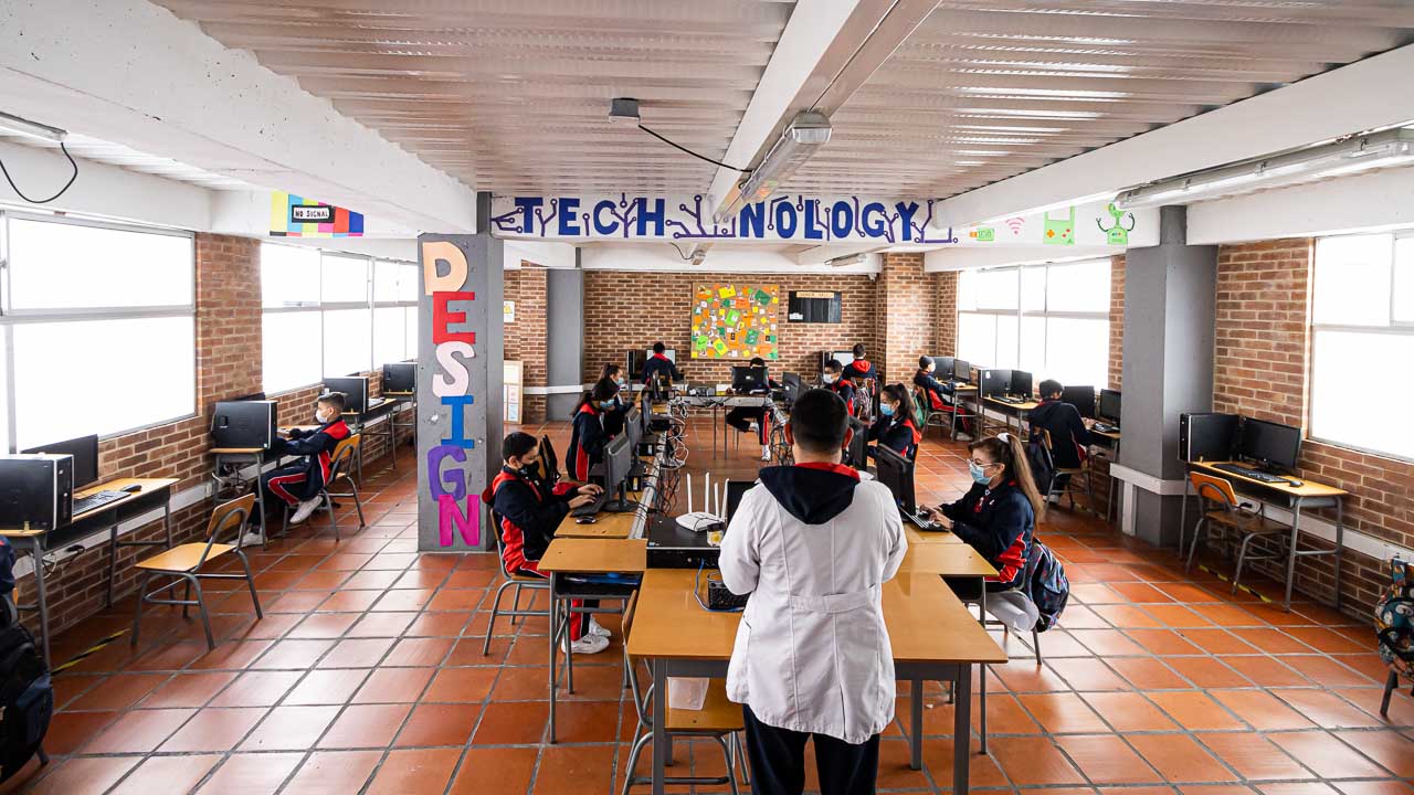Sala de tecnología con computadores y estudiantes