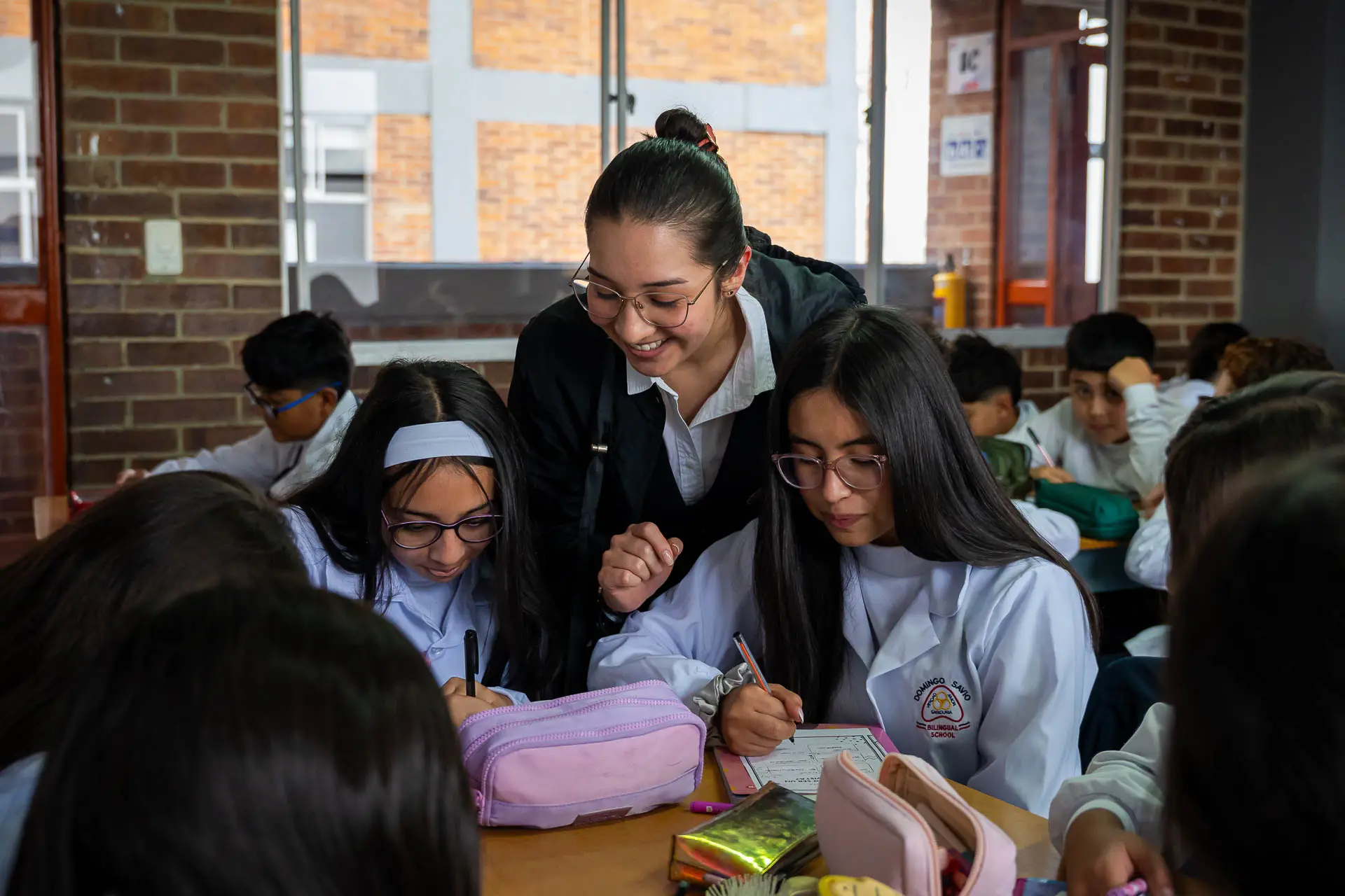 Docente acompa&ntilde;ando a estudiantes en una actividad de clase