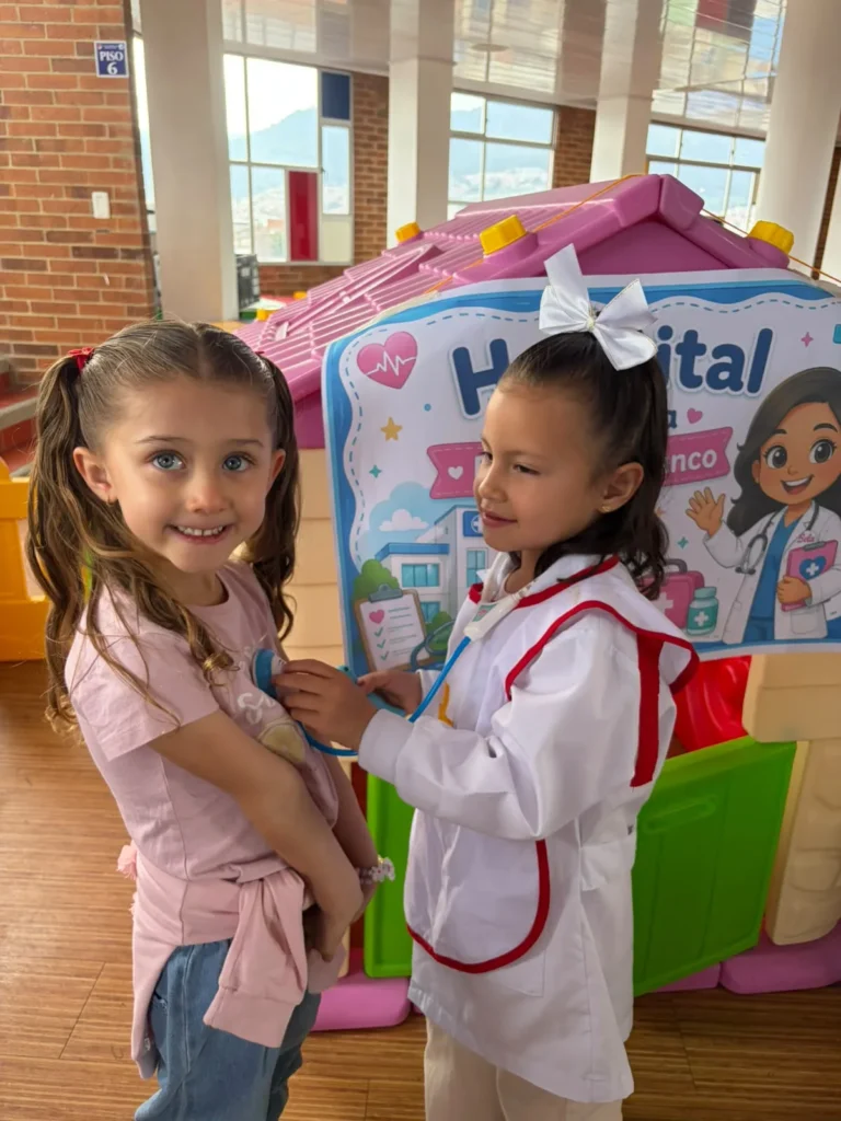 Niñas de Preschool participan en el hospital de SaviCity mediante juego simbólico.